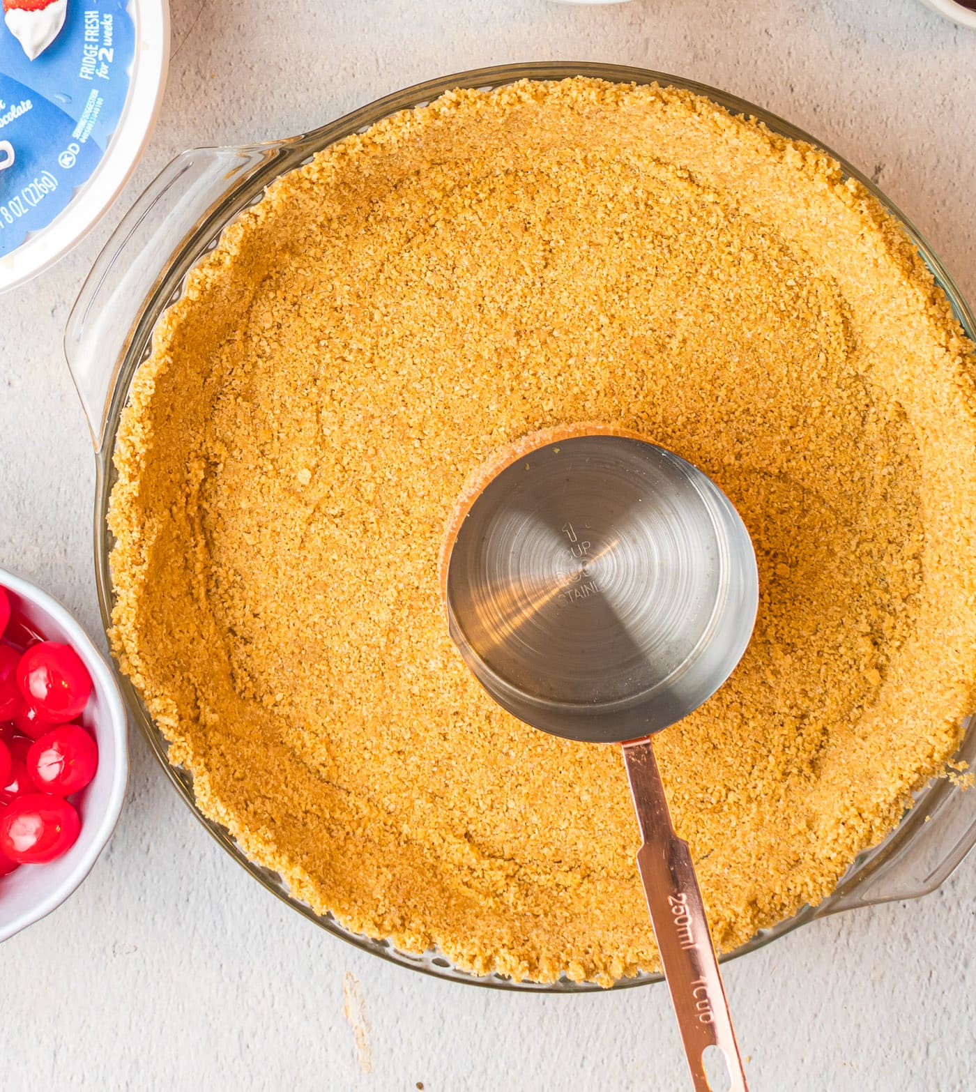 graham cracker crust with measuring cup in a pie pan