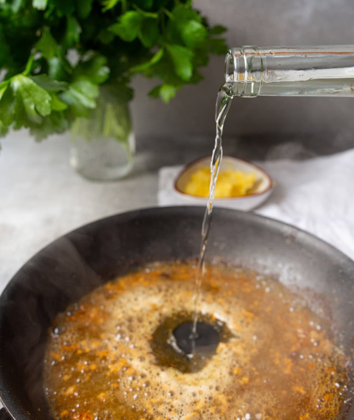 pouring white wine into skillet