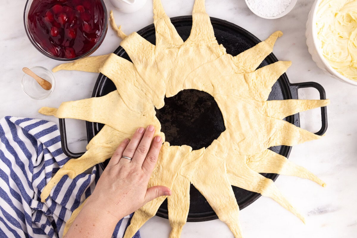 hand pressing down crescent rolls