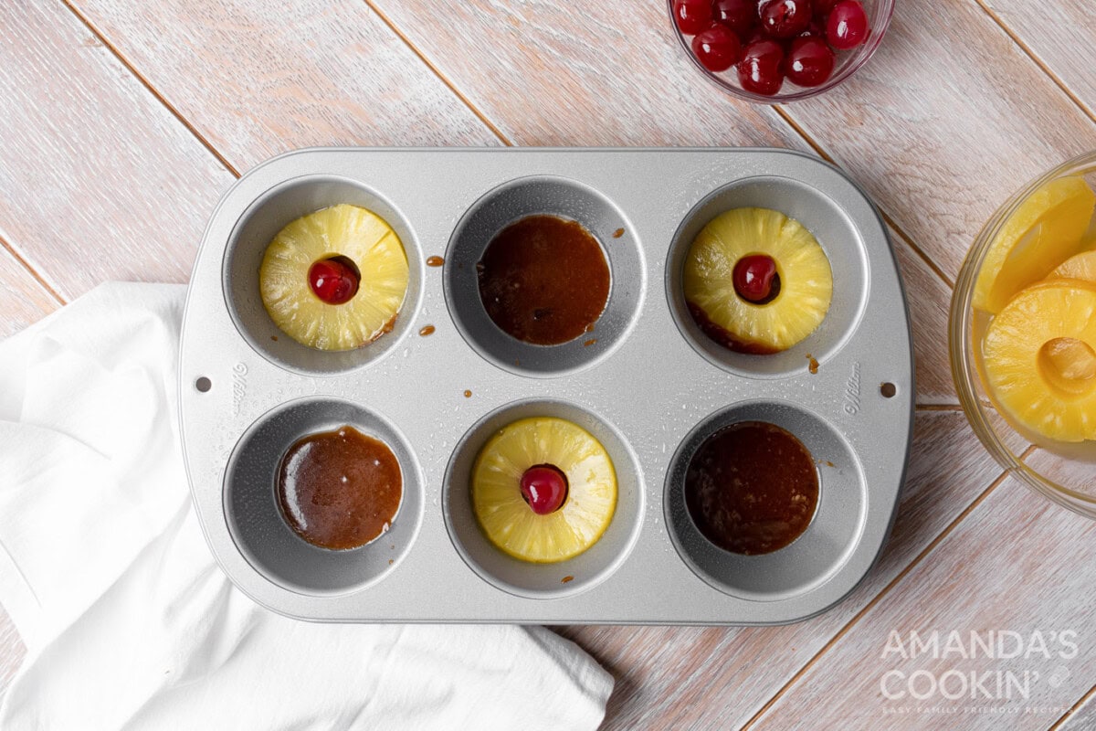pineapple rings on top of brown sugar mixture in a muffin tin