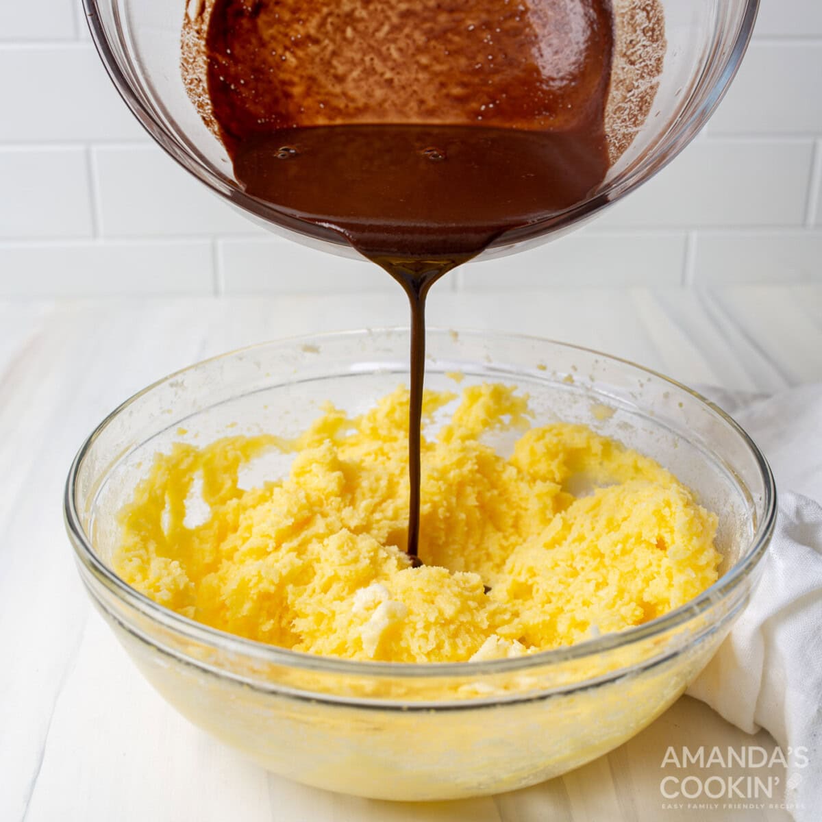 sugar and butter mixture in a bowl, pouring melted chocolate in