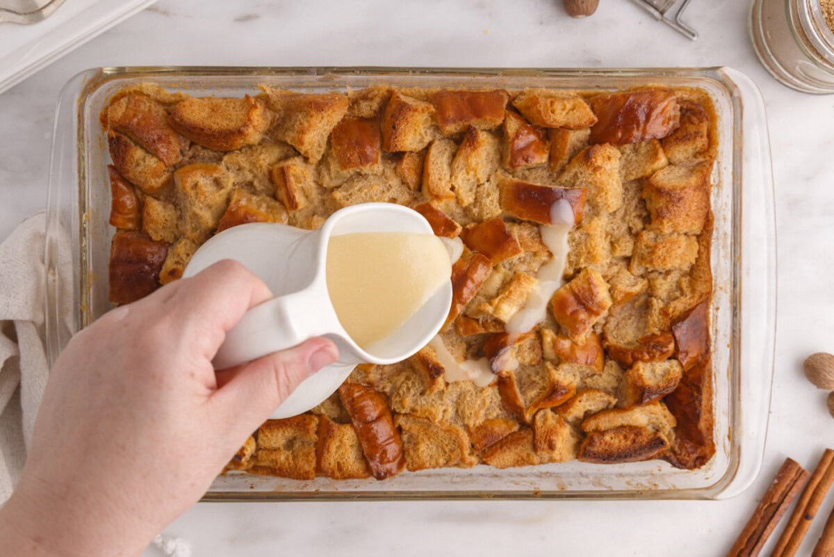 pouring vanilla sauce over bread pudding