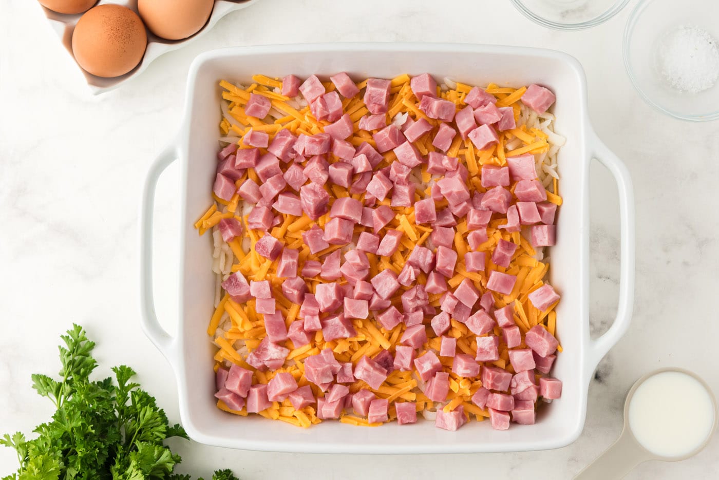 cubed ham on top of cheese in casserole dish