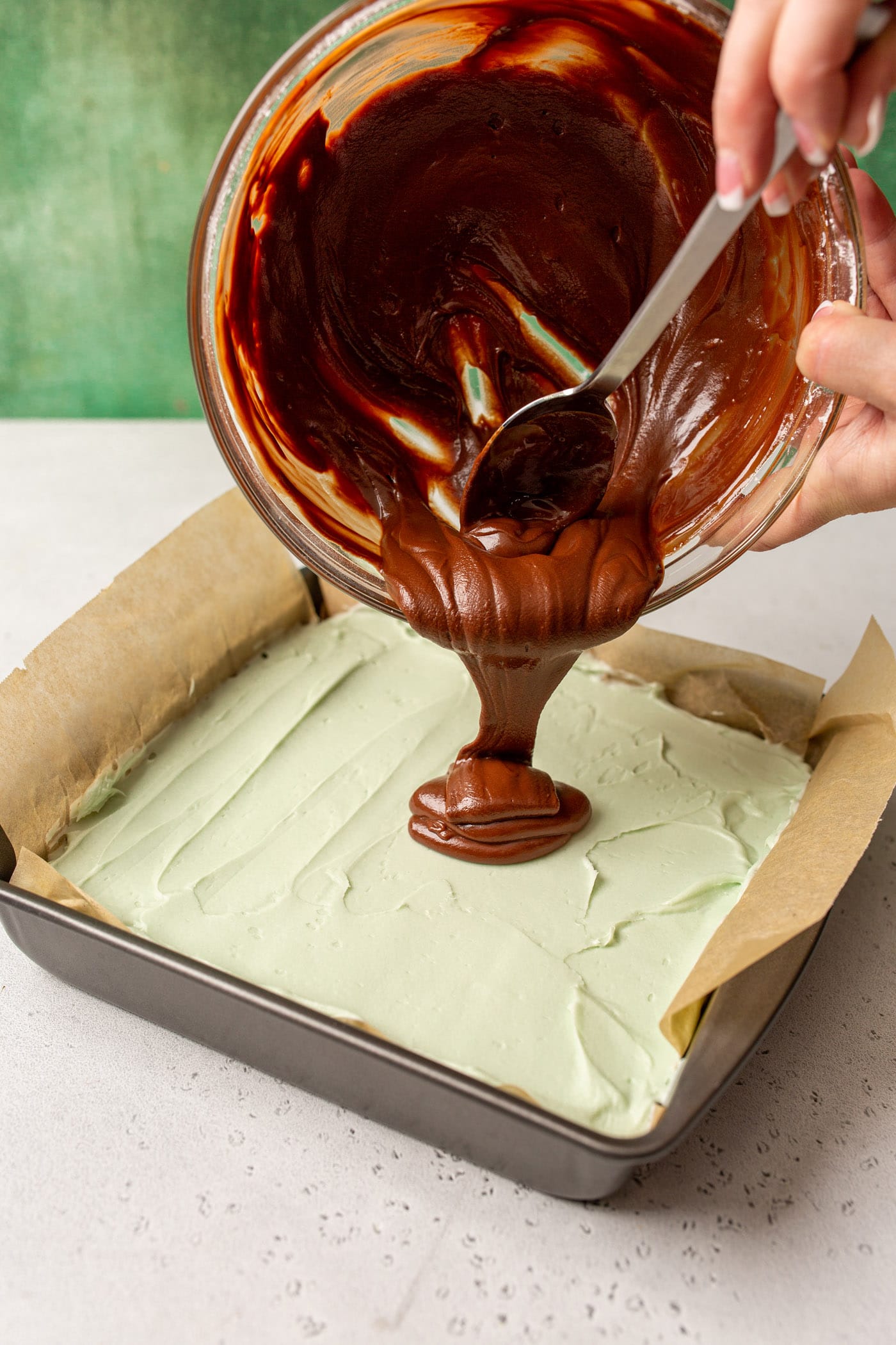 pouring chocolate ganache onto mint chocolate brownies