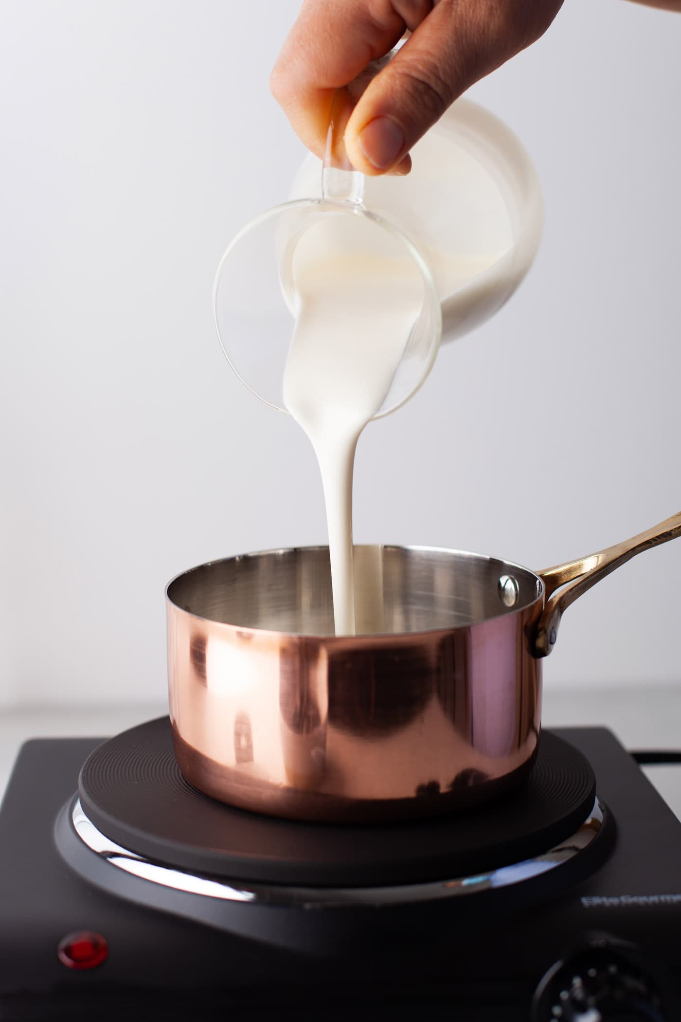 pouring whipping cream in a saucepan