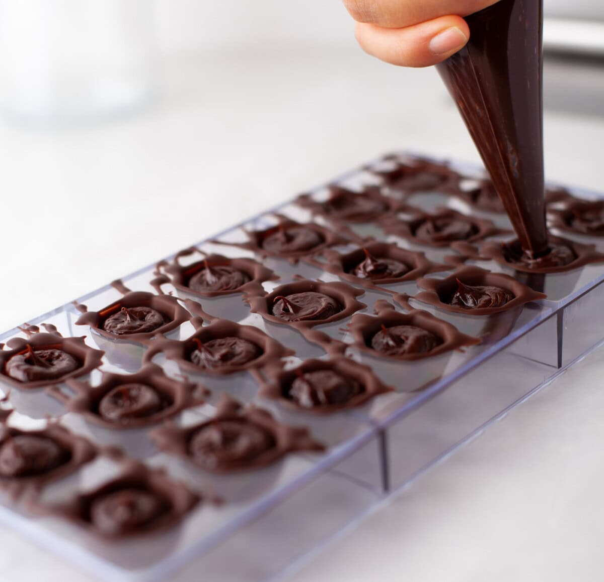 piping ganache into chocolate mold