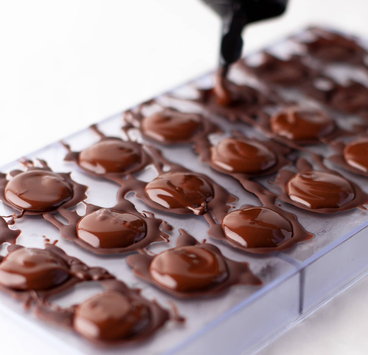 squeezing chocolate over candy mold