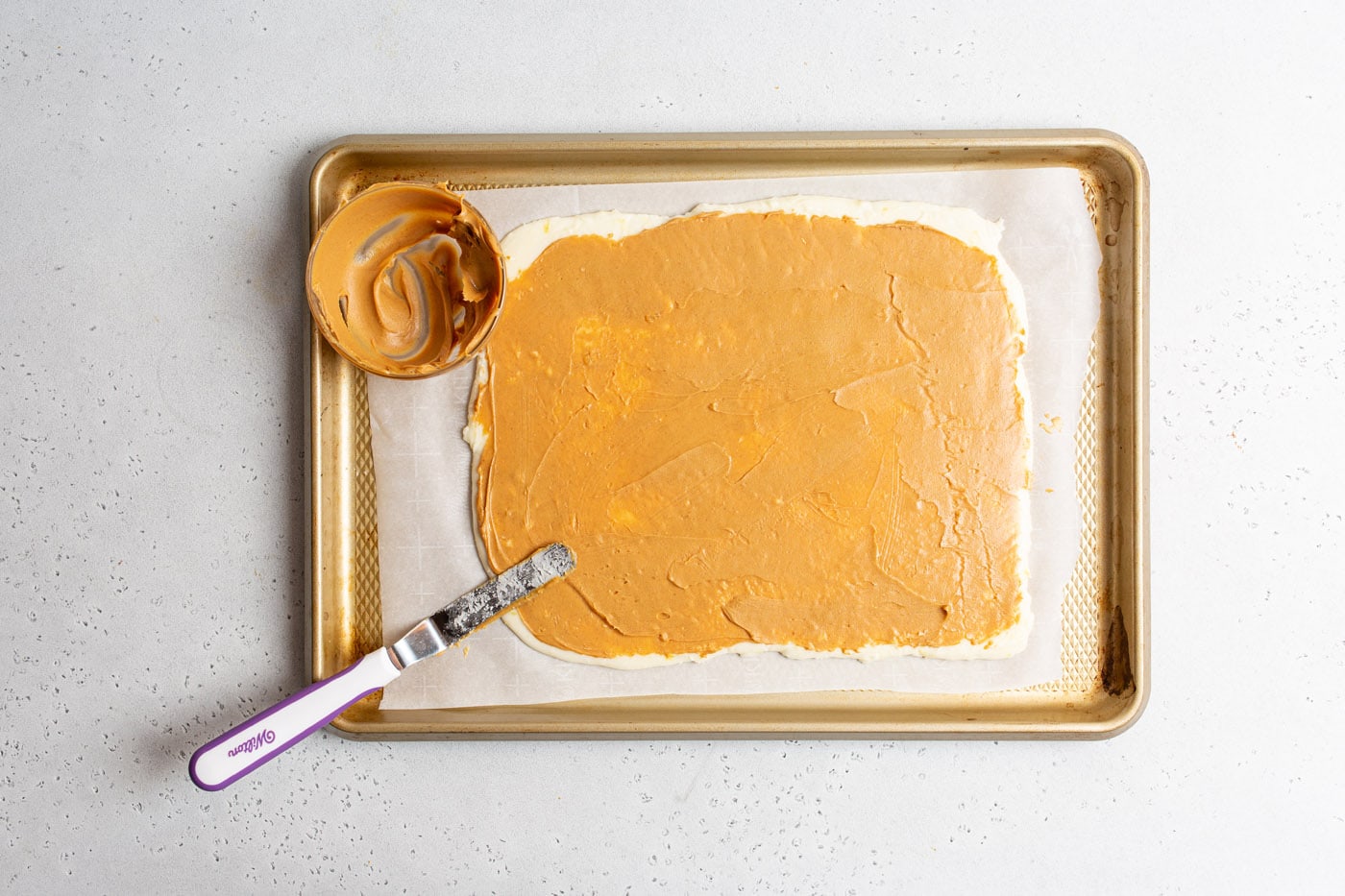 offset spatula smoothing peanut butter on potato dough