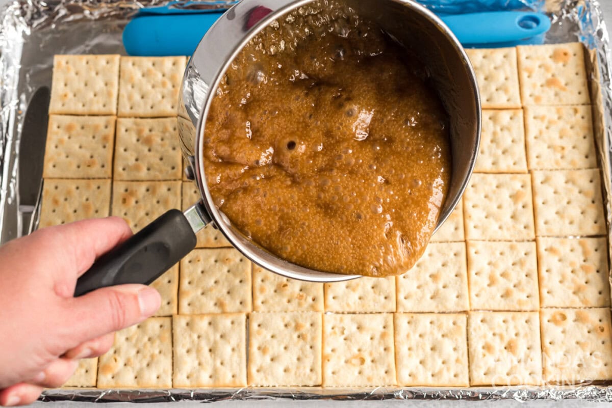 pouring caramel over saltine crackers