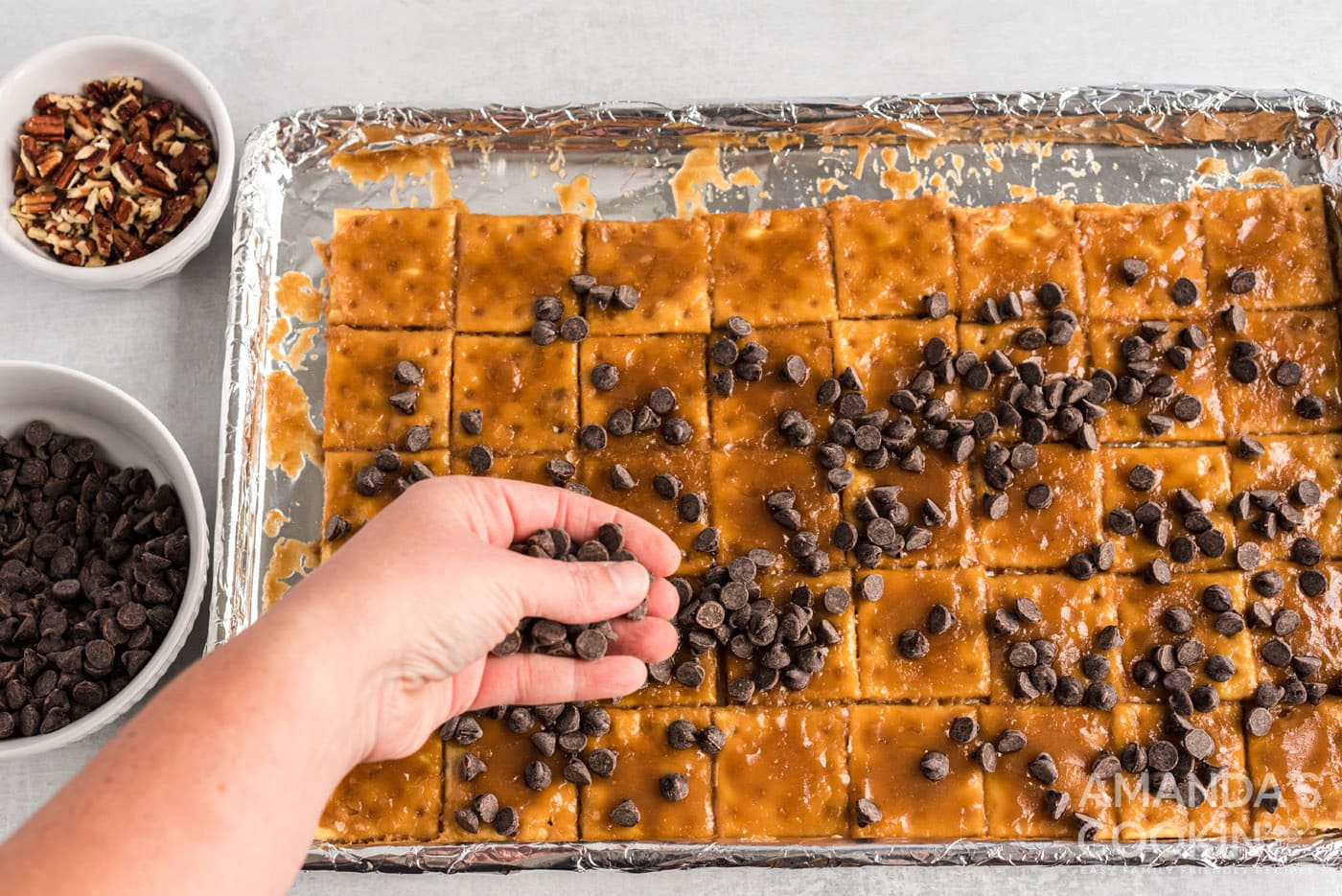hand sprinkling chocolate chips onto caramel crackers