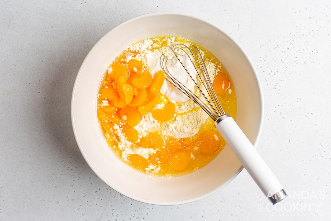 yellow cake mix, vegetable oil, sour cream, eggs, and mandarin oranges in a mixing bowl