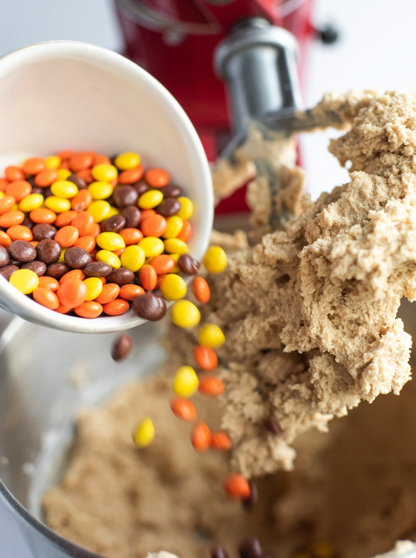 pouring Reese's pieces into cookie dough