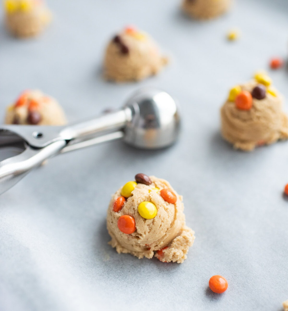 cookie scoop adding dough balls to parchment paper lined baking sheet