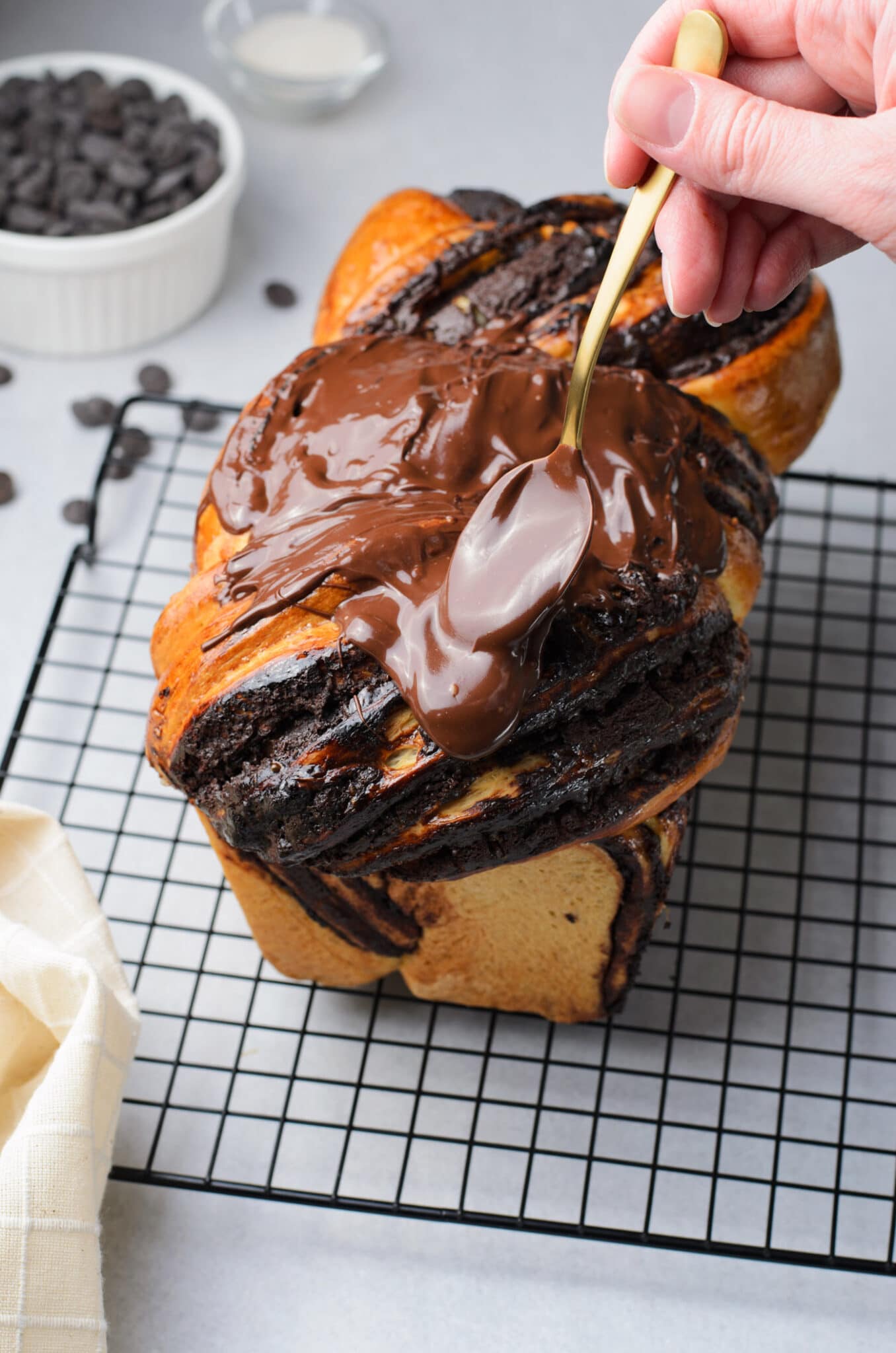 spooning chocolate glaze onto Chocolate Babka