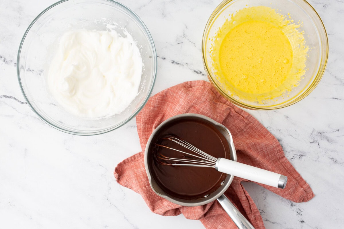 chocolate ganache, whisked egg yolks, and beaten egg whites in bowls