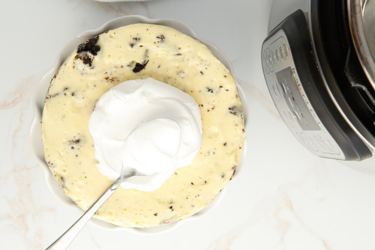 spreading whipped cream on oreo cheesecake