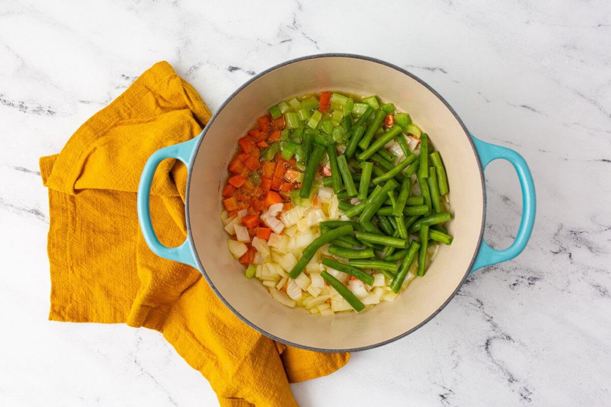 onions, carrots, celery, and green beans in a stockpot