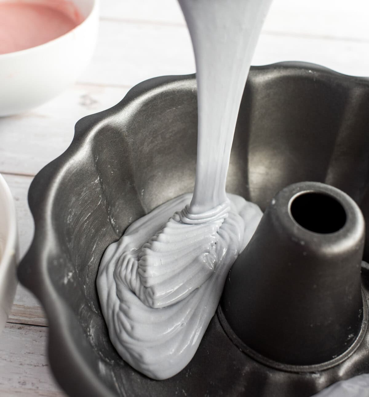 pouring pastel purple cake batter into bundt pan