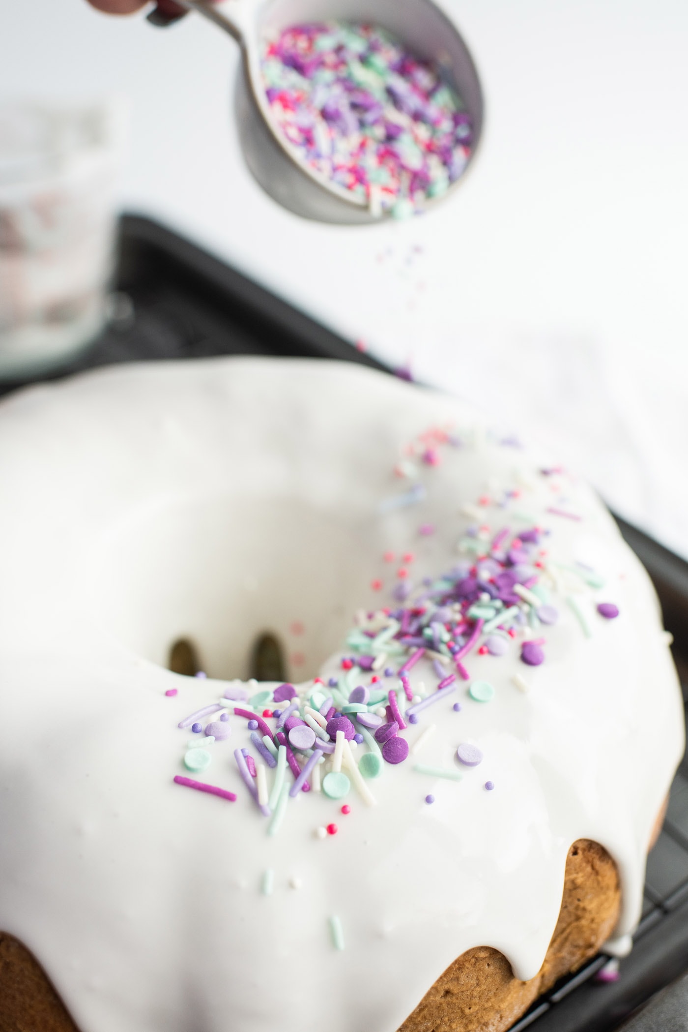 adding colorful sprinkles to glazed bundt cake