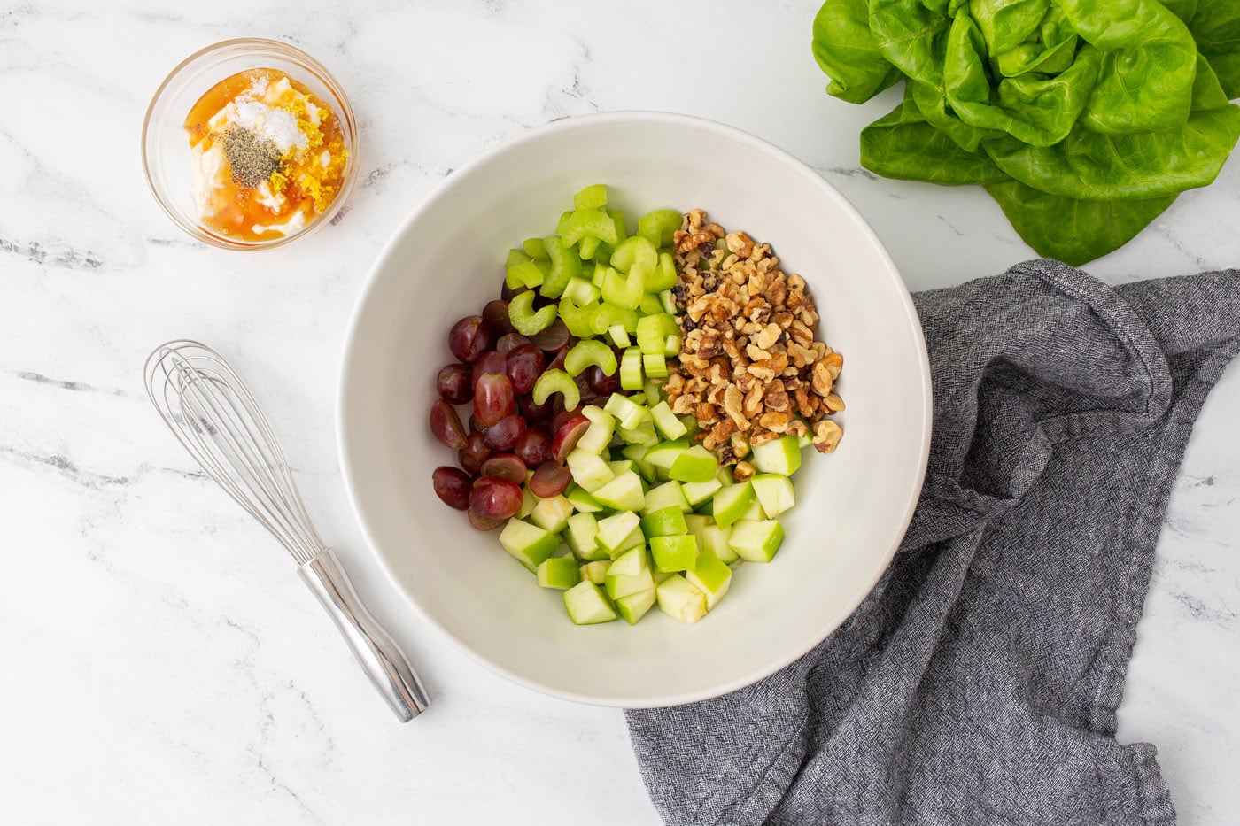 apples, celery, walnuts, and grapes in a bowl