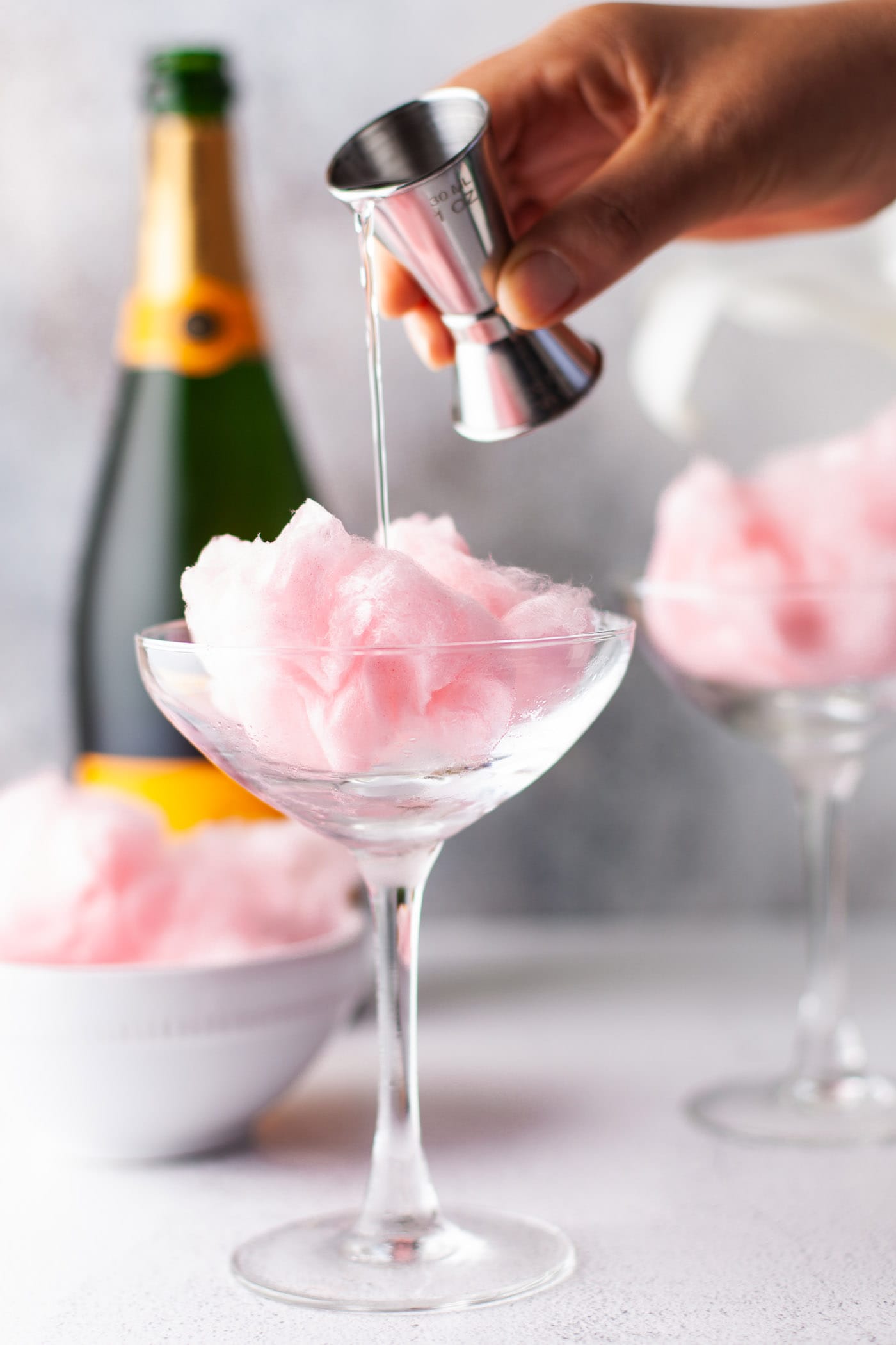hand pouring orange liquor into glass of cotton candy