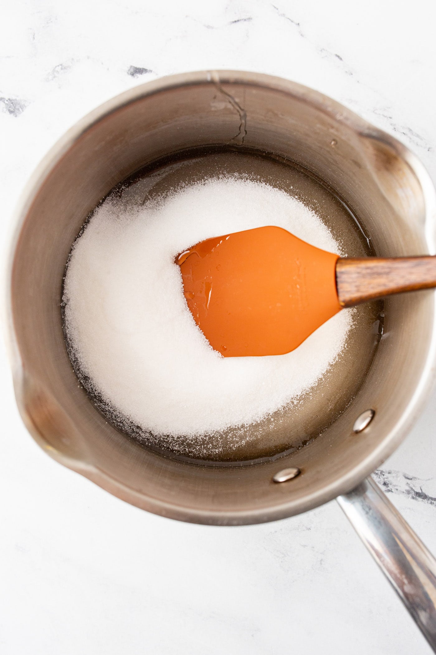 corn syrup and sugar with a rubber spatula in a pot