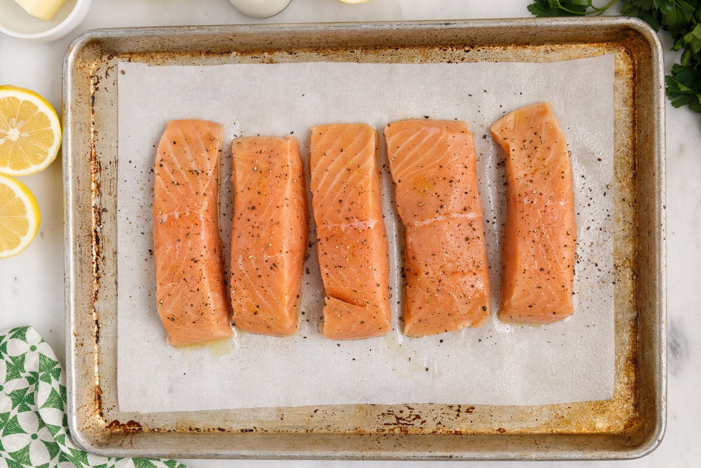 seasoned salmon filets on baking sheet