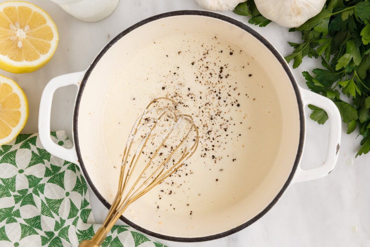 whisking lemon cream sauce in a saucepan