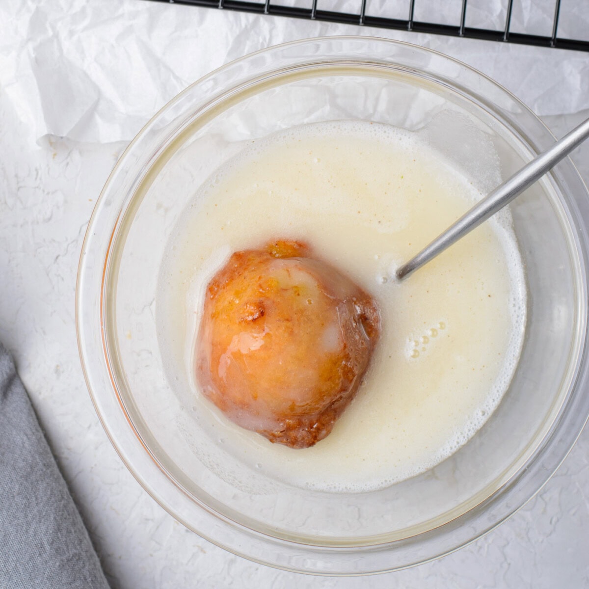 dunking banana fritter into sugar glaze