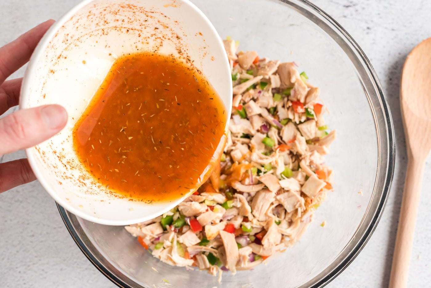 pouring cajun dressing over chicken salad
