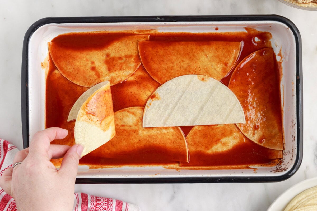 dipping tortillas in enchilada sauce