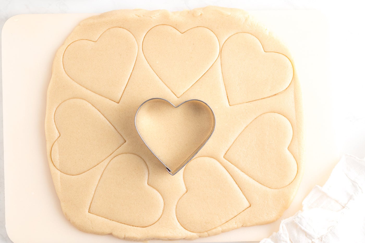 heart shaped cookie cutter cutting sugar cookie dough