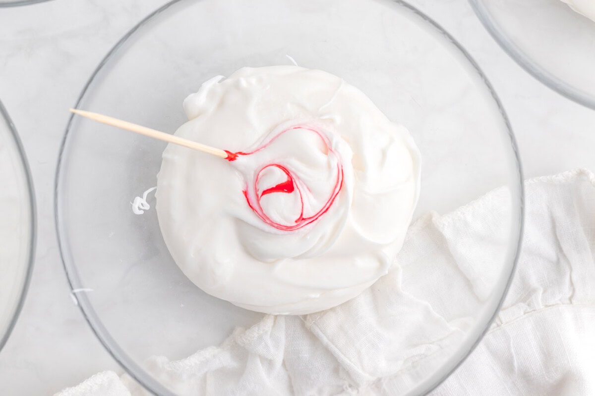 toothpick mixing red food color into white frosting