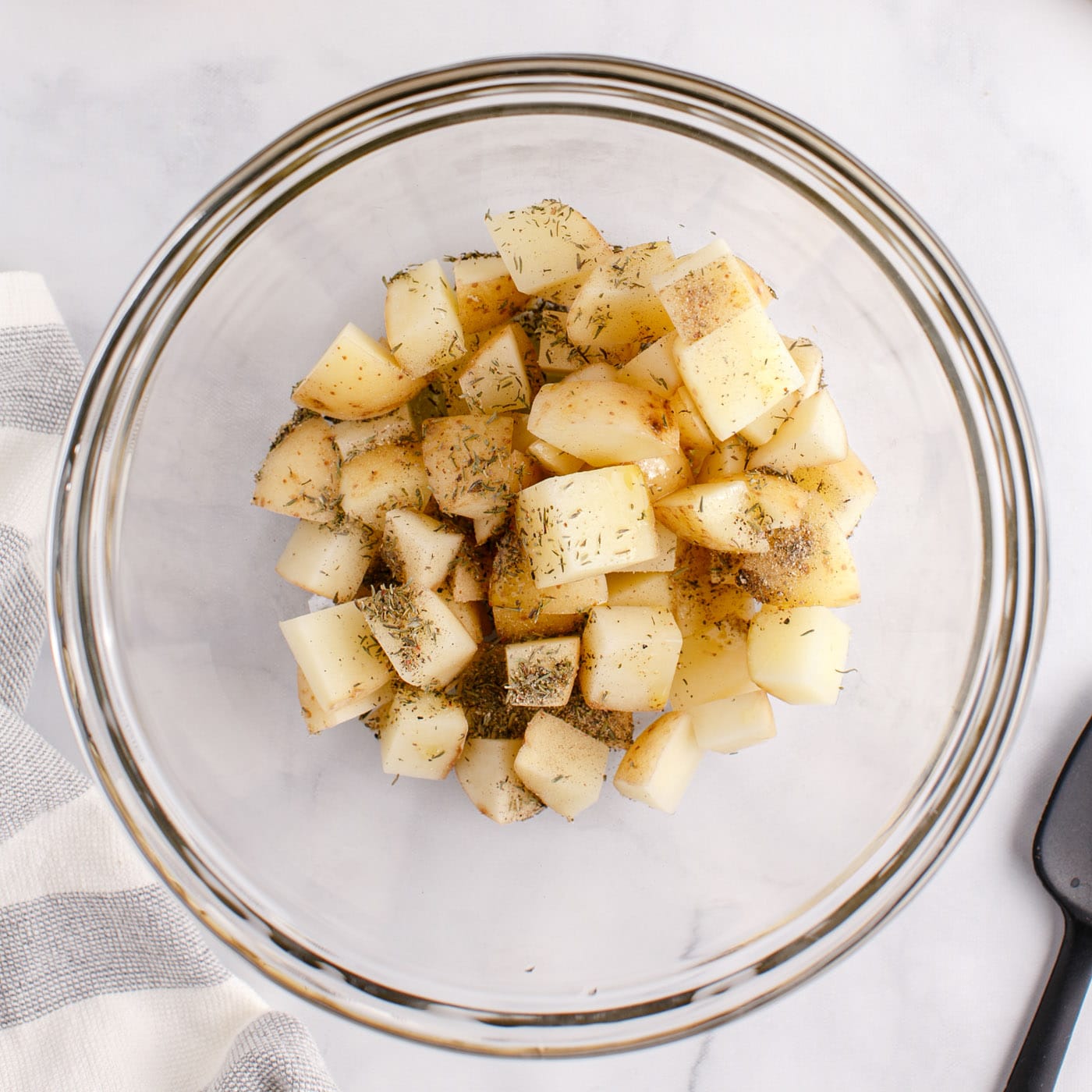 cubed potatoes in a bowl with seasonings and oil