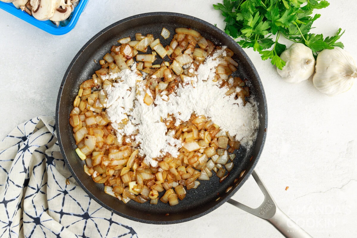 flour added to onions and garlic in a skillet
