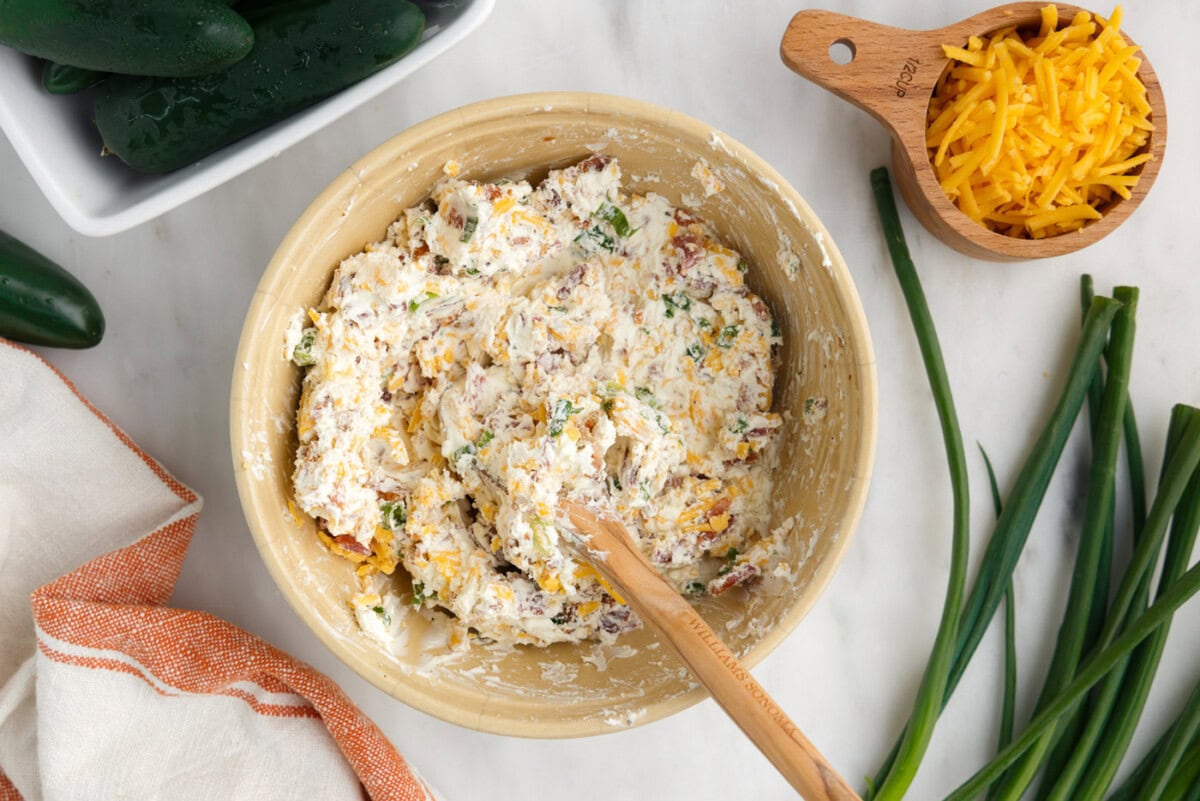 cream cheese, cheddar cheese, green onion, seasonings, and bacon mixed in a bowl