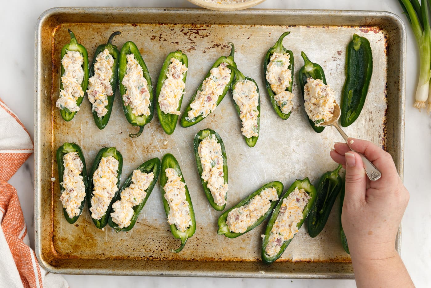 jalapeno poppers with cream cheese and cheddar on baking sheet
