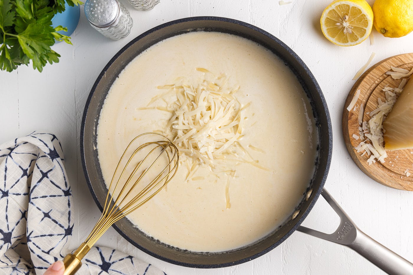 whisking parmesan cheese into creamy lemon garlic sauce