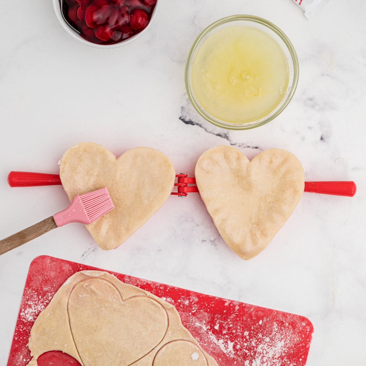 brushing heart shaped pie dough with egg wash