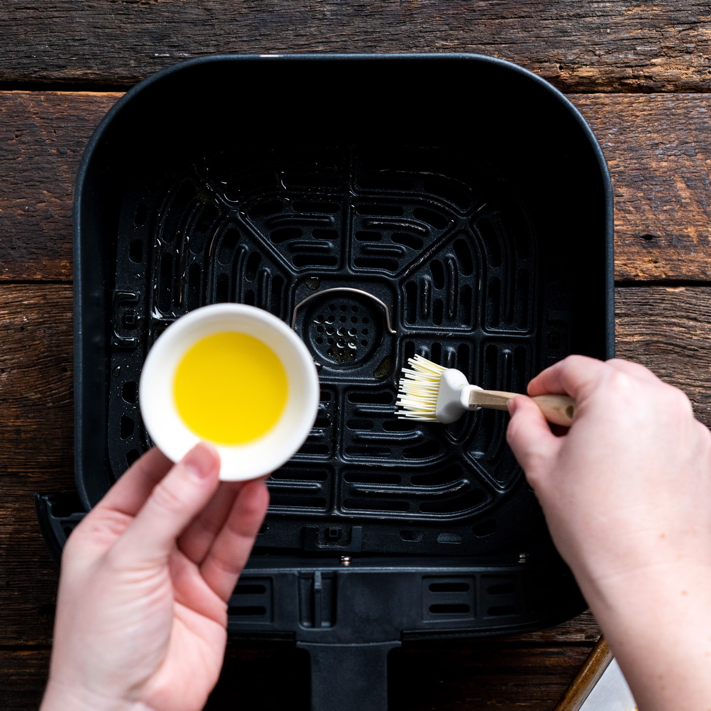 brushing air fryer with olive oil