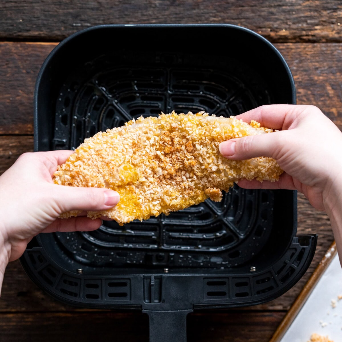 breaded fish above air fryer basket