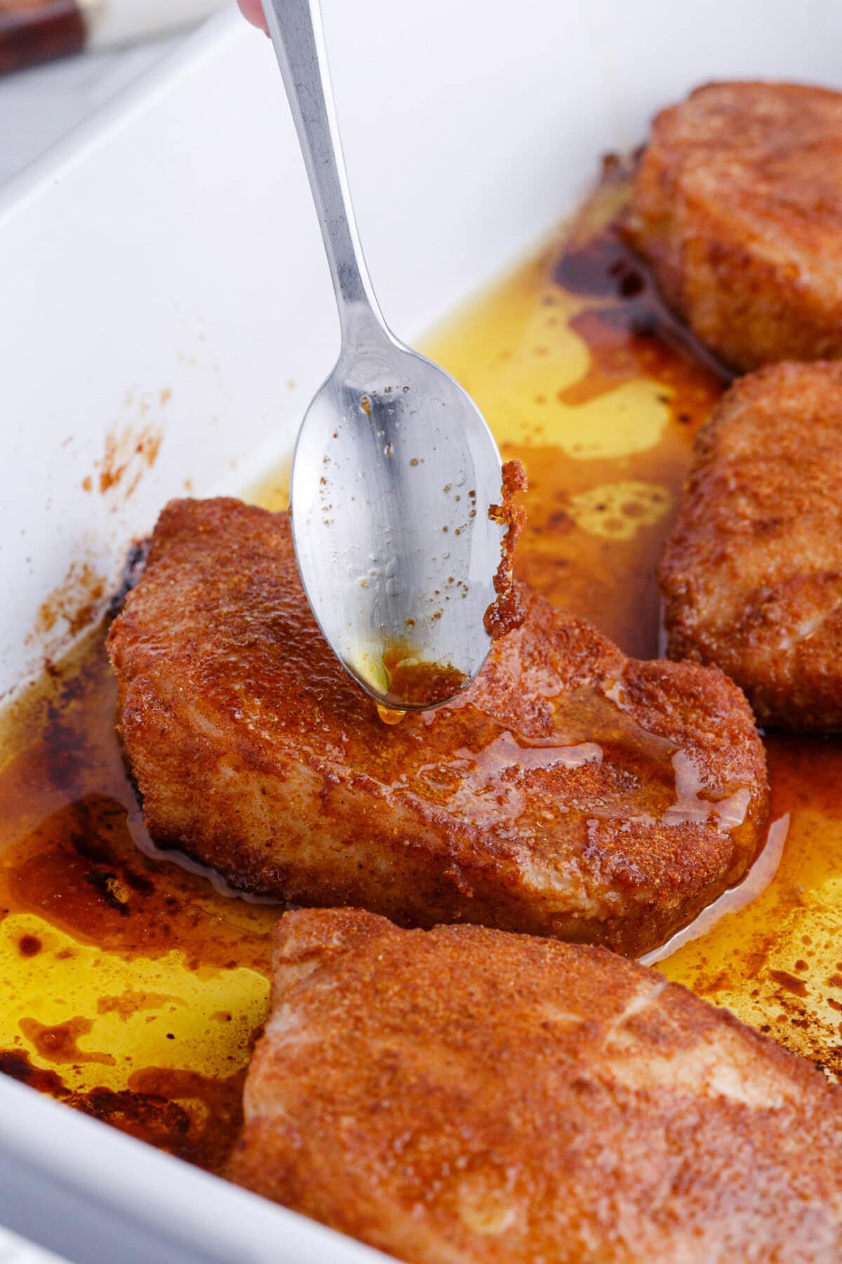spooning juices over Baked Pork Chops