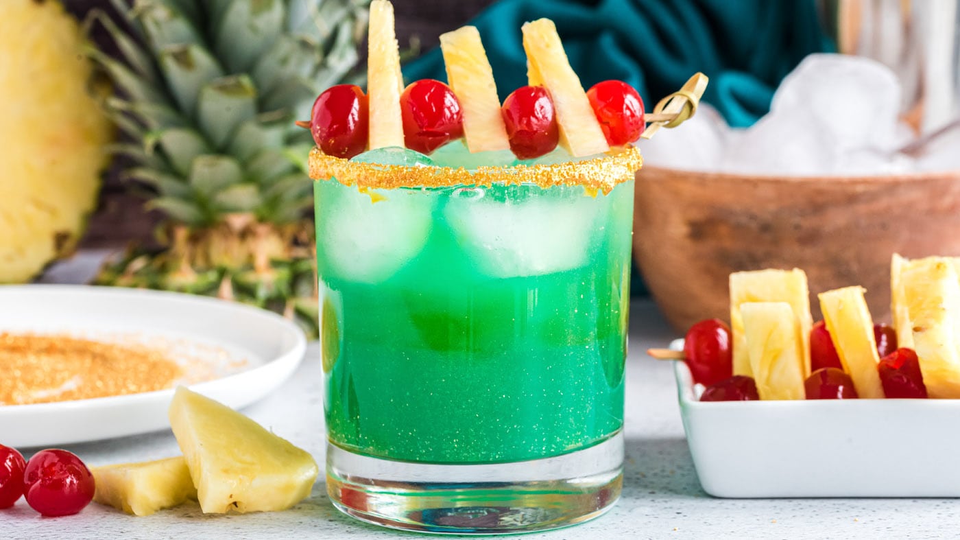 Pineapple juice and blue curacao mix together to create a festive green colored cocktail that fits r
