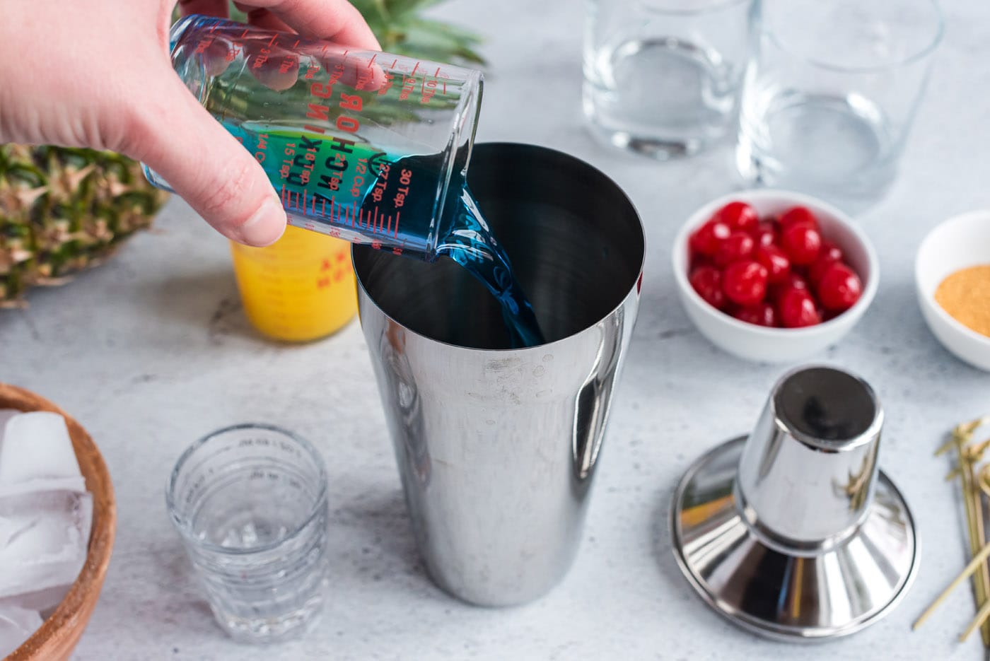 pouring blue curacao into cocktail shaker