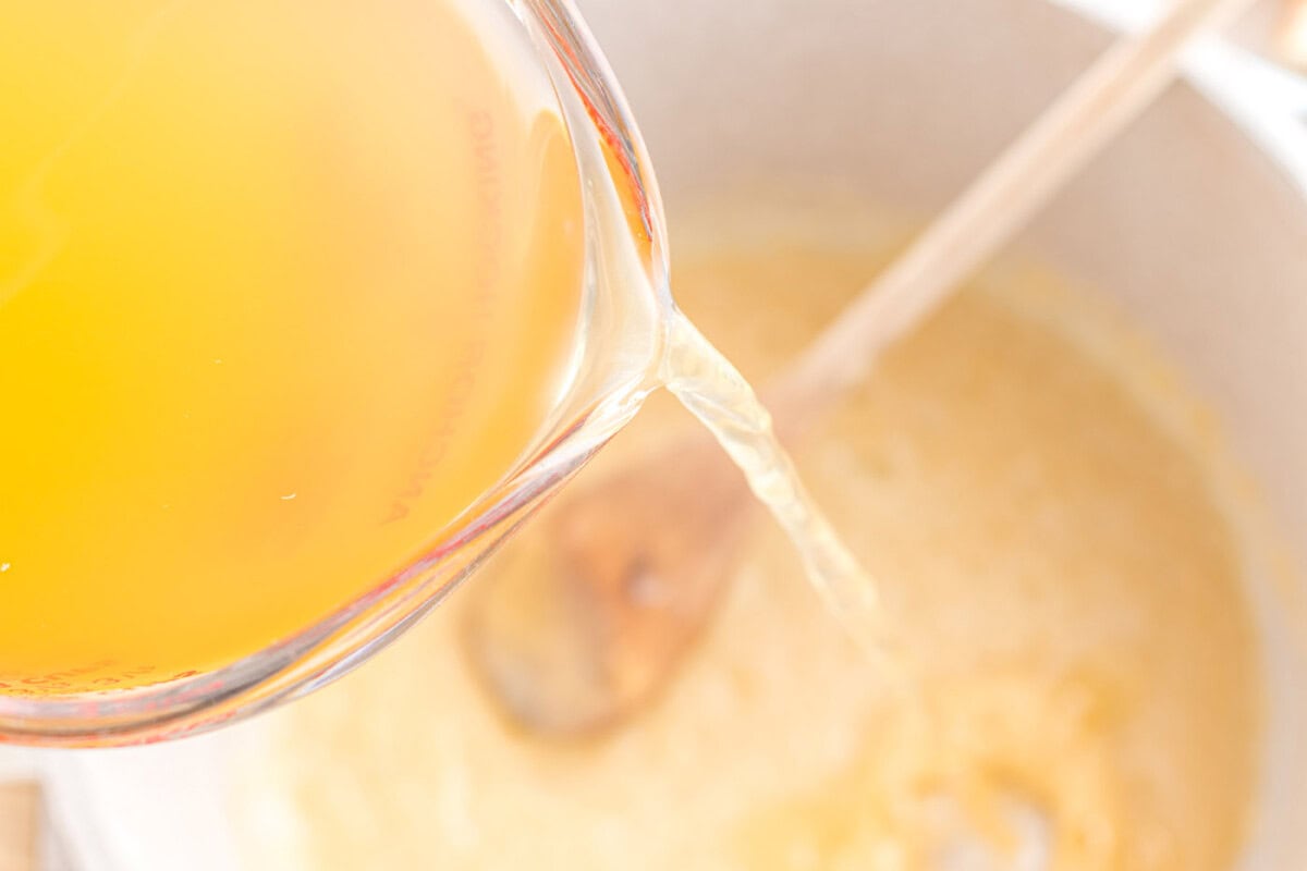 pouring chicken stock into a pot
