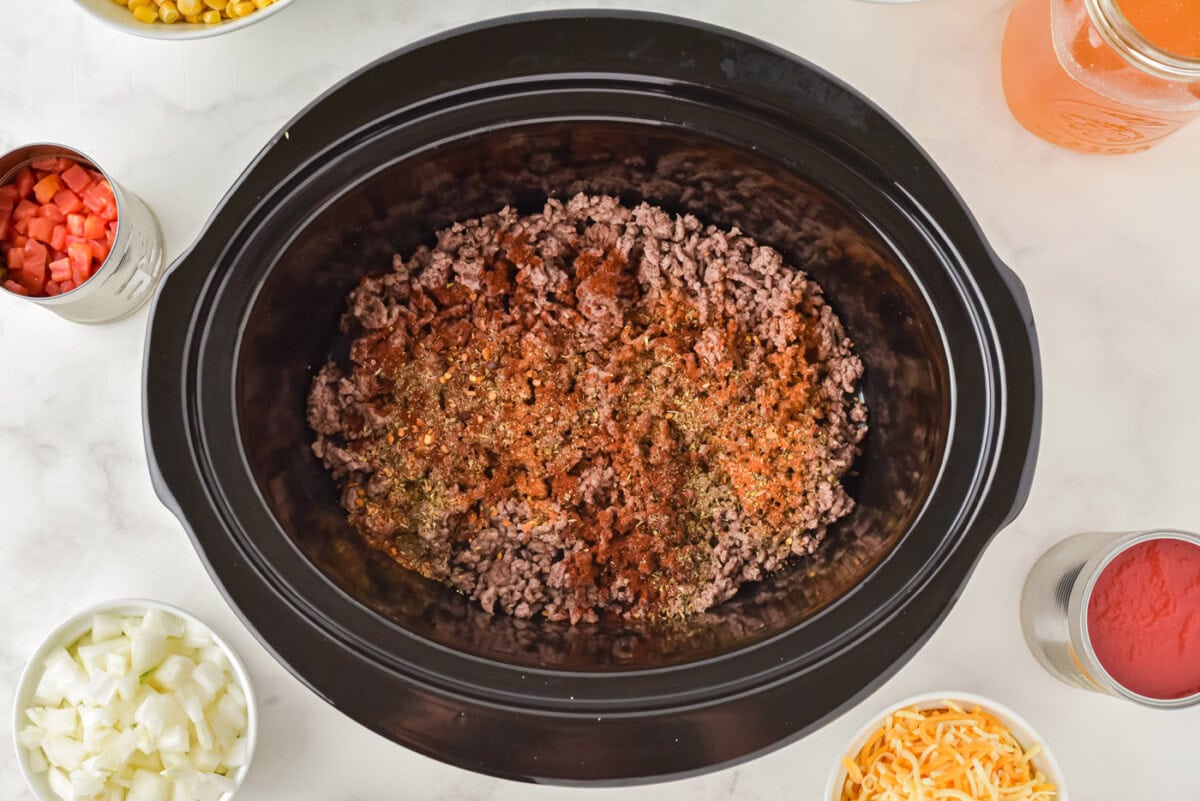seasonings on top of ground beef in a crockpot