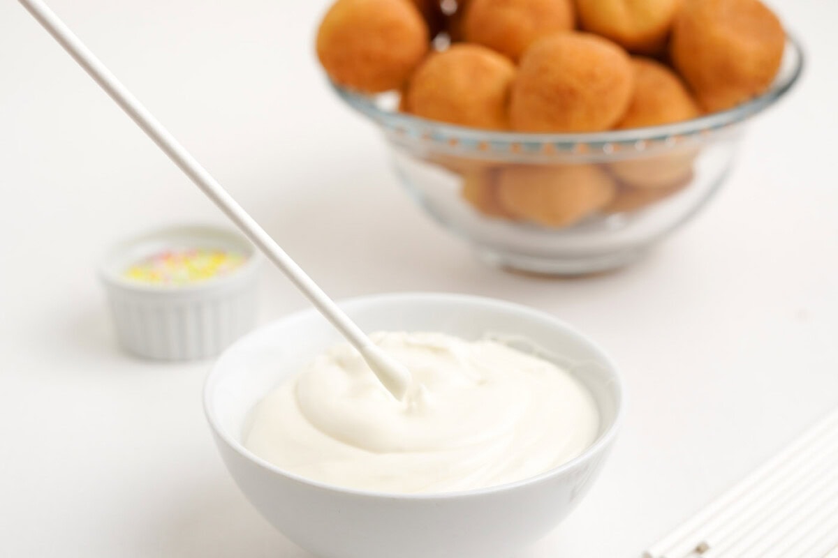 melted white chocolate in a bowl with cake pop stick