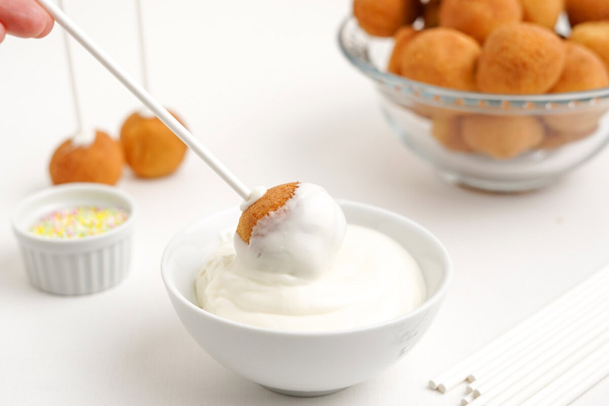 dipping donut hole cake pop into chocolate