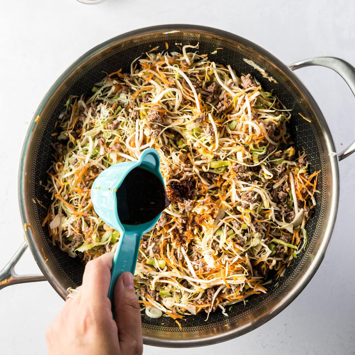 adding sauce to egg roll in a bowl