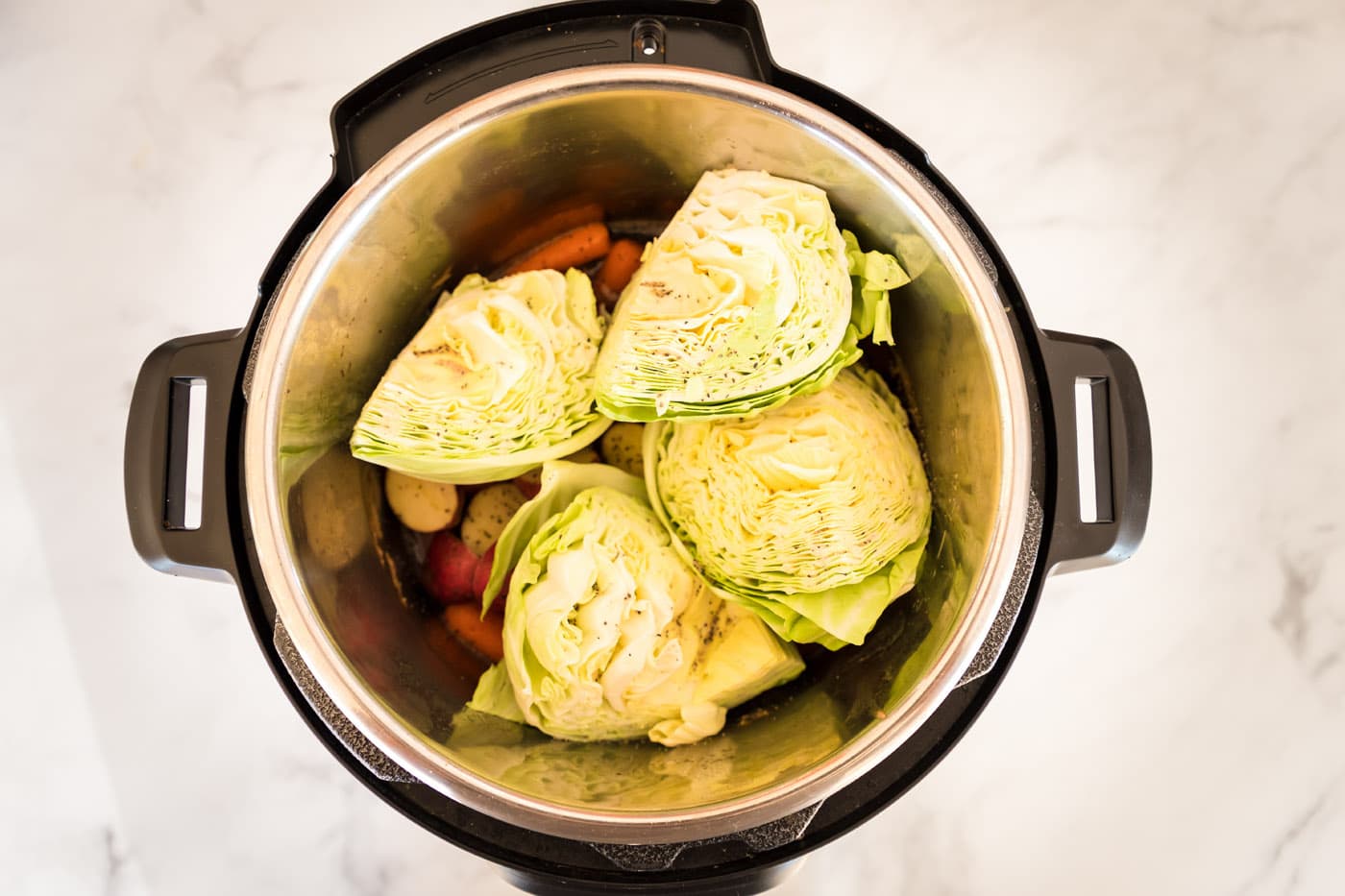 cabbage over baby potatoes and carrots in instant pot